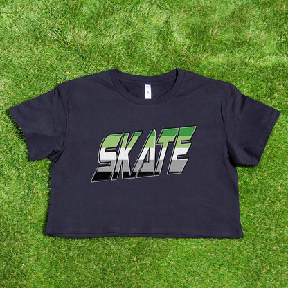 Featured against a vibrant background, the SKATE Aromantic pride flag crop tee by Gay Skate showcases "SKATE" in bold, green and white gray and black block letters on a black crop tee seamlessly blending the aro flag's colors.