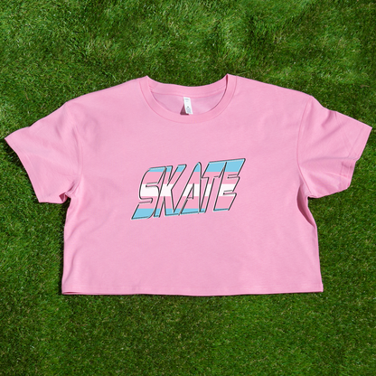 The "SKATE Trans Flag - locally printed crop tee" by Gay Skate is a black T-shirt featuring the word "SKATE" in bold, colorful, and stylized letters on the front. The letters have a gradient effect with shades of pink, blue, and white reminiscent of the transgender flag, giving the design a vibrant and dynamic appearance. The T-shirt has a cropped fit perfect for streetwear fashion.