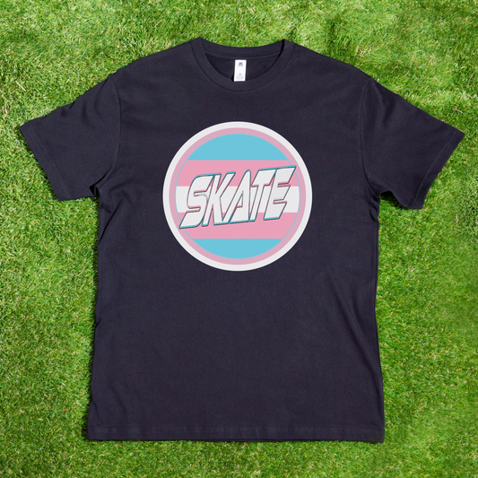 The product is a "Trans Flag Circle Gay Skate - Local hand pressed t-shirt" by Gay Skate. This black, 100% cotton t-shirt features a circular graphic in the center with the word "SKATE" in stylized white text. The graphic has a pink, blue, and white color scheme that resembles the Trans Pride flag, perfect for showing off your Gay Skate pride. The shirt is displayed on a plain white background.