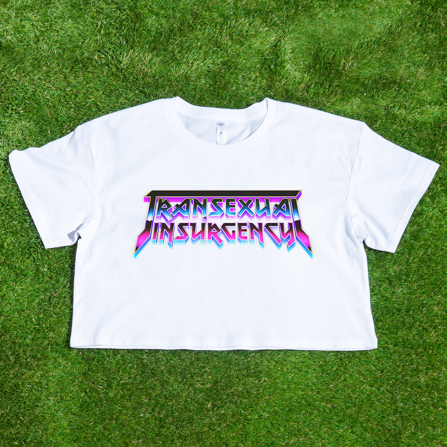 White crop tee with 'Transsexual Insurgency' text on a grass background