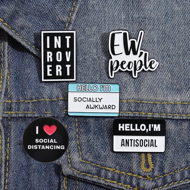 Collection of pins on a denim jacket with phrases like 'Introvert', 'Ew people', 'Hello I'm Socially Awkward', and 'Hello, I'm Antisocial'.