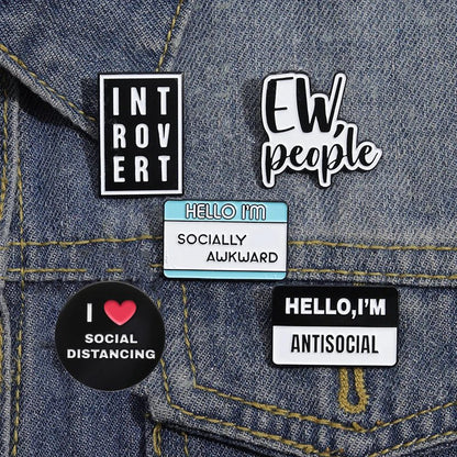 Collection of pins on a denim jacket with phrases like 'Introvert', 'Ew people', 'Hello I'm Socially Awkward', and 'Hello, I'm Antisocial'.