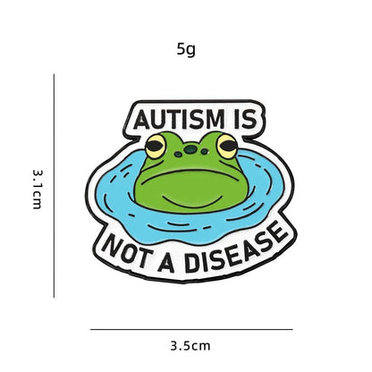 Enamel pin with a frog design and text 'Autism is not a disease' with measurements on a white background.