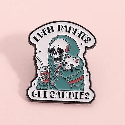 Enamel pin with a skeleton holding a cat and text 'Even Baddies Get Saddies' 