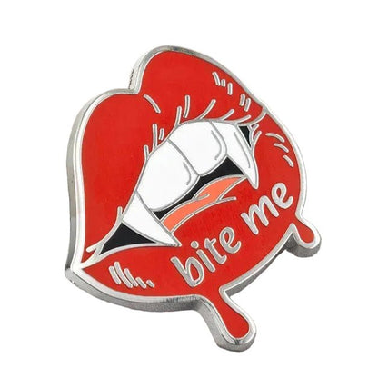 A red enamel pin shaped like lips with white teeth and the words 'bite me' in silver script