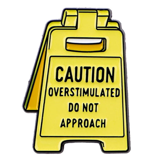 Yellow caution neurodiversity sign badge with text 'Caution: Overstimulated Do Not Approach'
