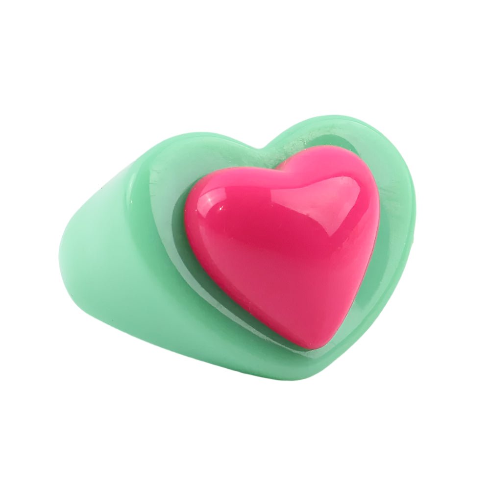 The Chunky acrylic sweet heart ring by Gay Skate features a playful, pink heart on a mint green base against a plain white background, celebrating colorful combinations.