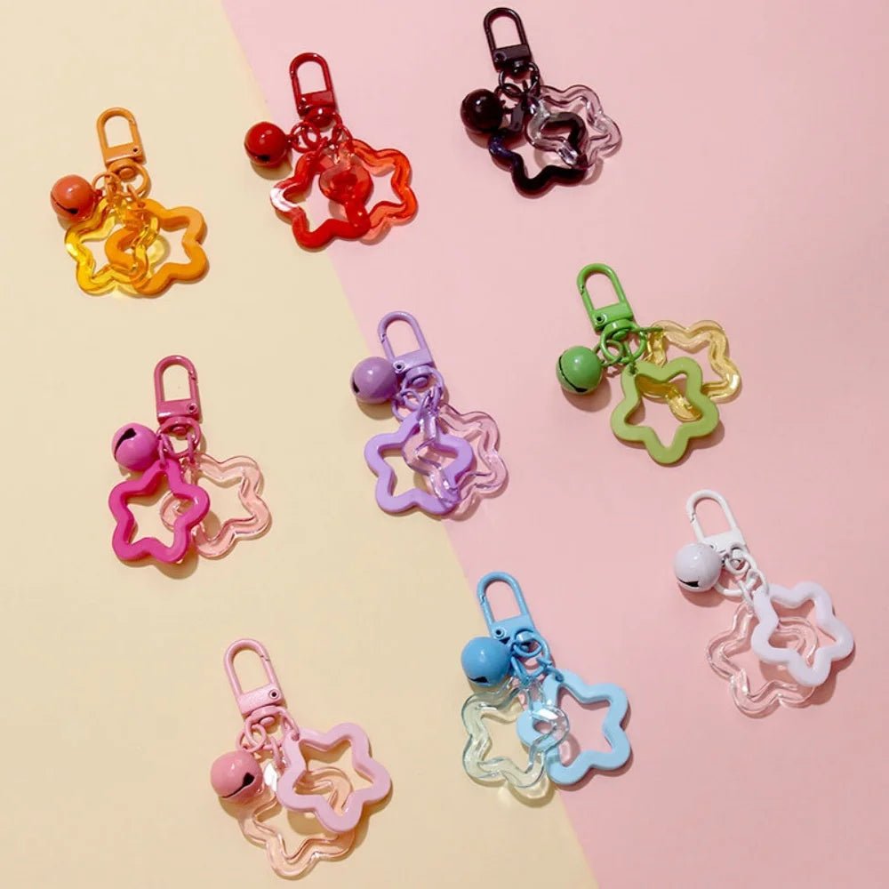 Colorful star-shaped keychains with bells on a two-tone pink and yellow background