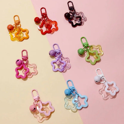 Colorful star-shaped keychains with bells on a two-tone pink and yellow background