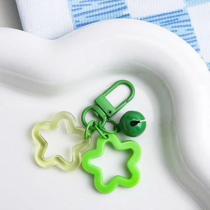 Green and clear star-shaped keychain with a bell on a white surface.