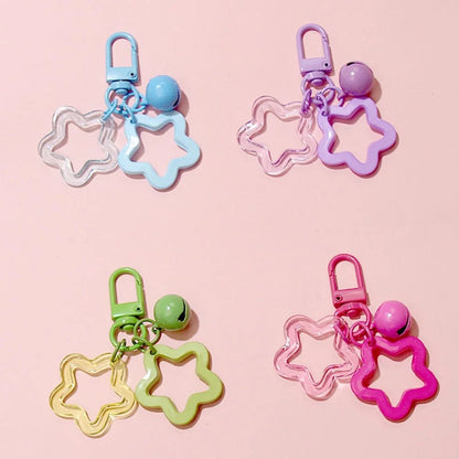 Four colorful star-shaped keychains on a pink background