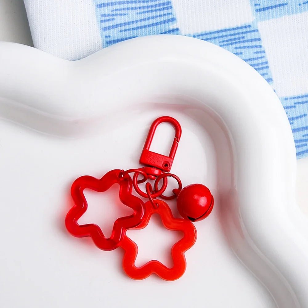 Red star-shaped keychain with a bell on a white surface