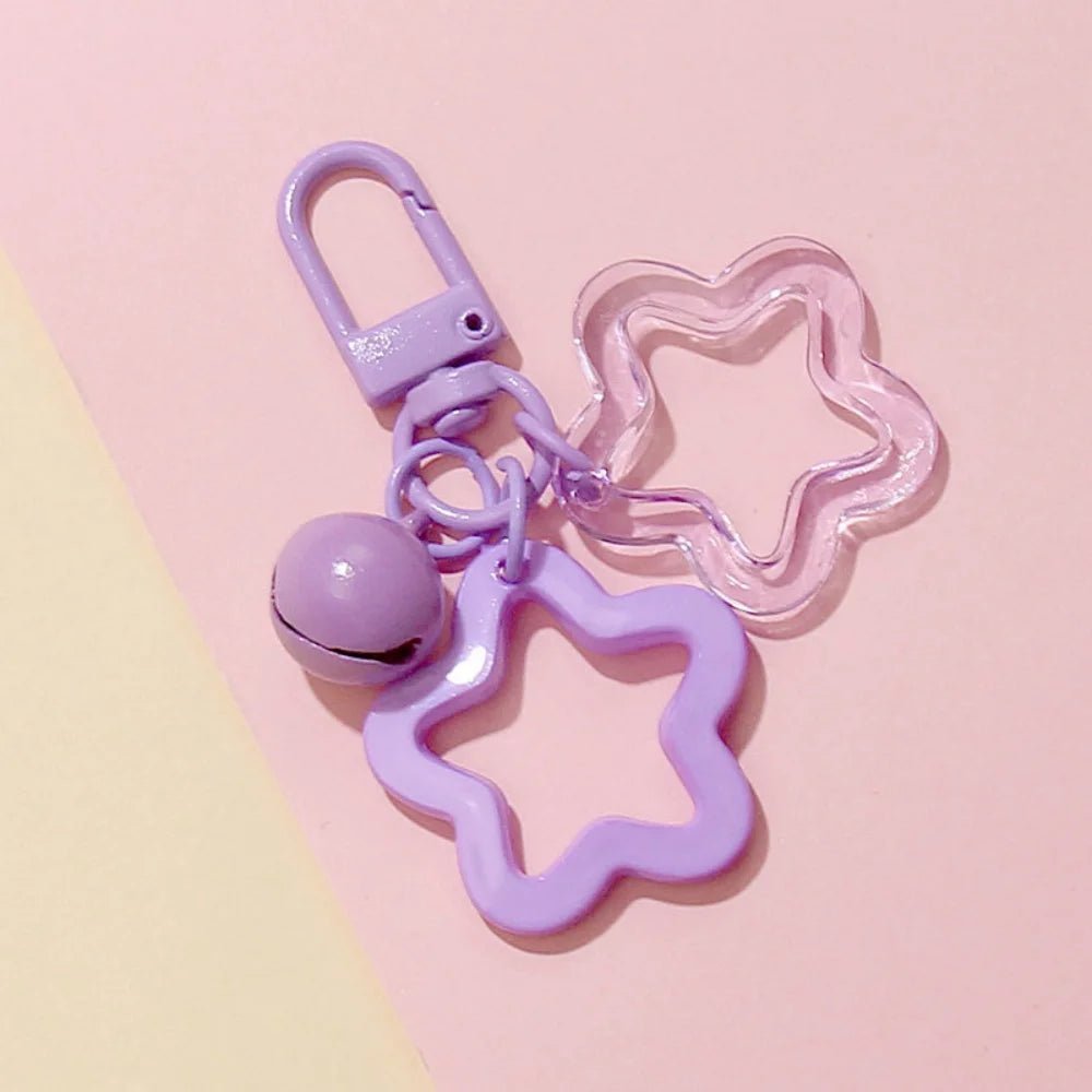 Star-shaped purple keychain with a bell on a pink background