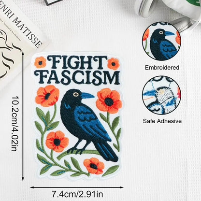Embroidered patch with a crow and flowers and text 'Fight Fascism' on a white background.
