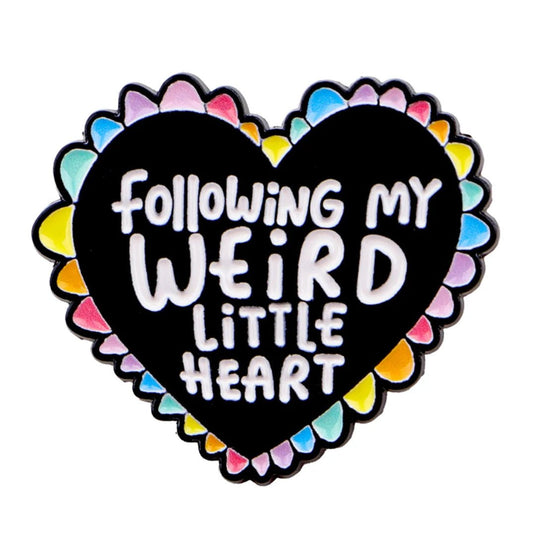 Heart-shaped enamel pin with arainbow border and text 'Following my weird little heart' 