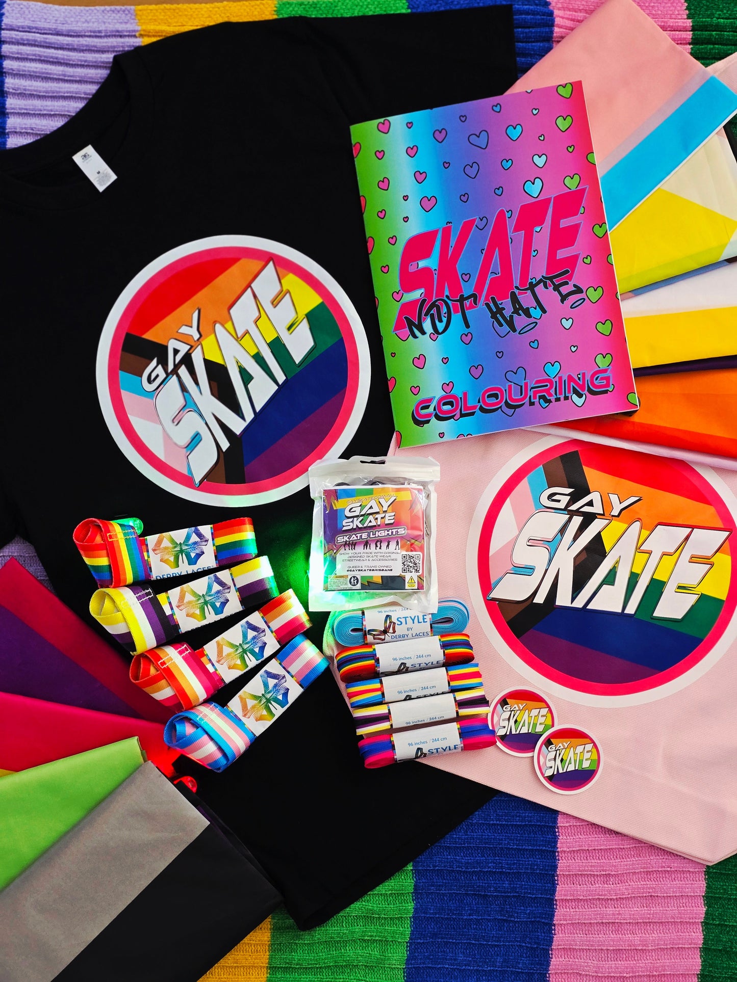 Collection of Gay Skate merchandise including t-shirts, stickers, and a coloring book on a colorful background.
