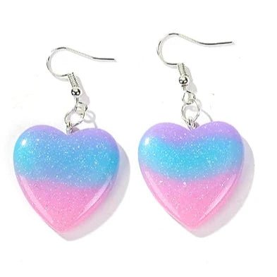 Introducing the Gradient Heart Drop Resin Earrings by Gay Skate, showcasing a captivating gradient design. These earrings feature heart shapes that transition from blue at the top to purple and then pink at the base, elegantly hanging from silver hooks.