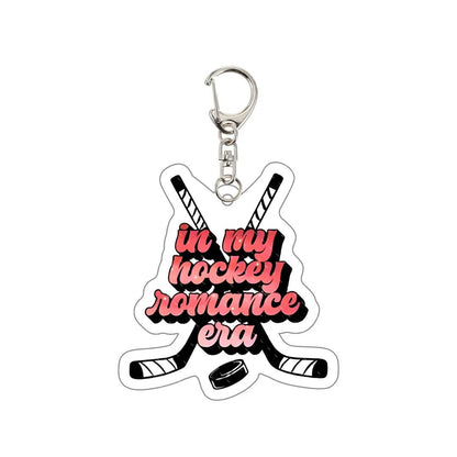 Keychain with crossed hockey sticks and text 'in my hockey romance era' 
