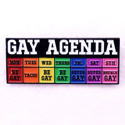 Colorful weekly planner style pin with 'GAY AGENDA' text: Be Gay, Tuesday Tacos, Be Gay, Super Gay, Brunch Gay