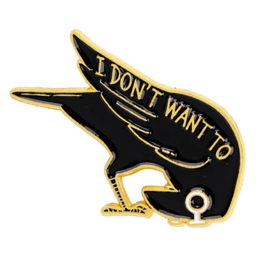 A black and gold enamel pin shaped like a bird with text 'I DON'T WANT TO' in gold lettering on its back