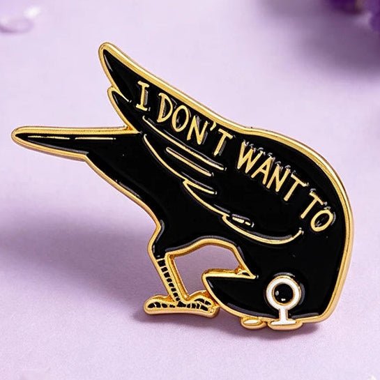 A black and gold enamel pin shaped like a bird with the text 'I DON'T WANT TO'