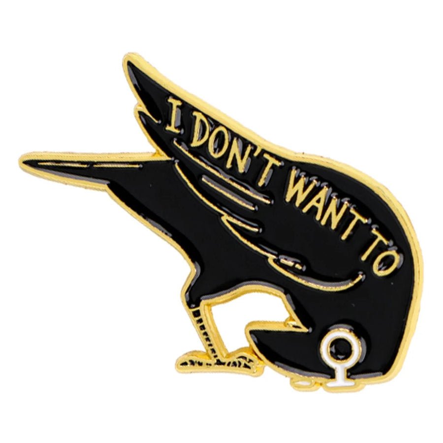 A black and gold enamel pin shaped like a bird with text 'I DON'T WANT TO' in gold lettering on its back