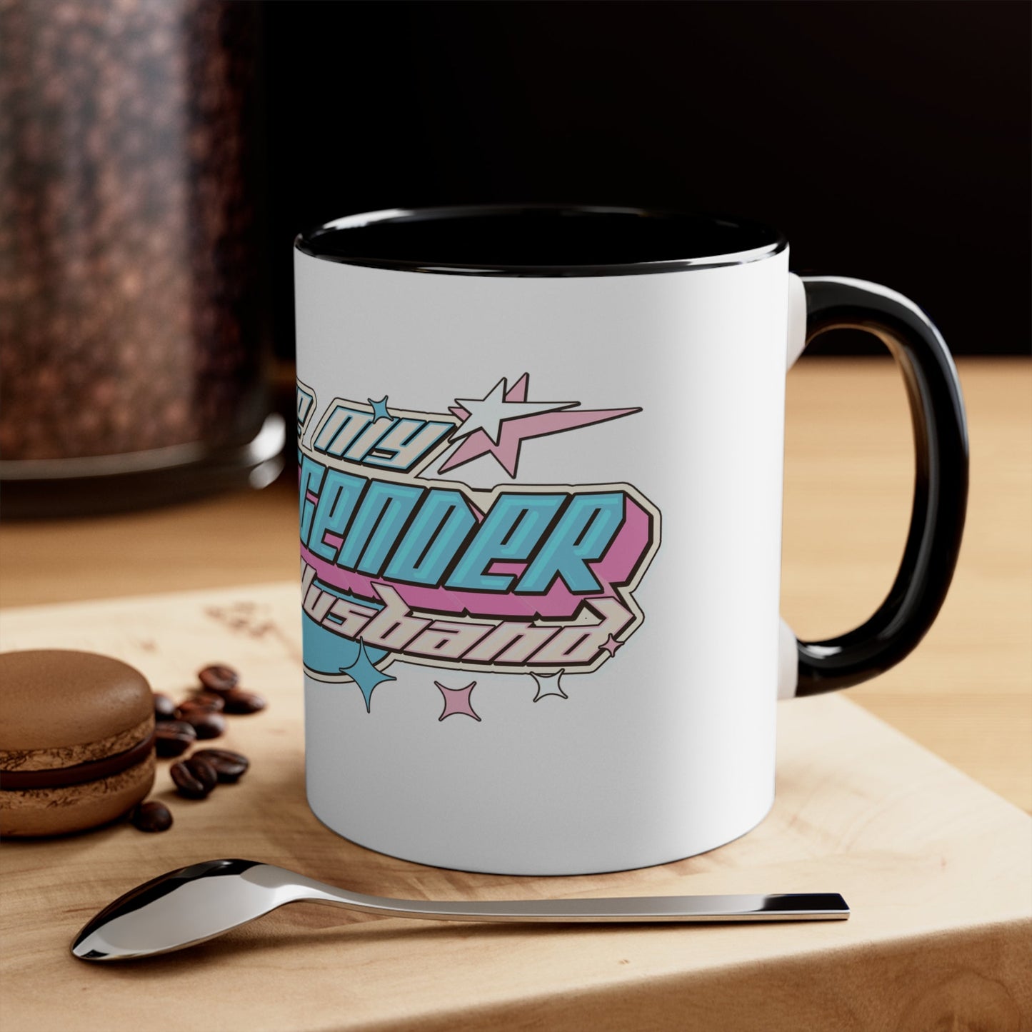 The "I Love My Transgender Husband" original design accent mug by Printify is a white mug with a vibrant interior, featuring bold, retro-styled text. The playful and celebratory design includes stars and geometric shapes in pastel pink, blue, and yellow.