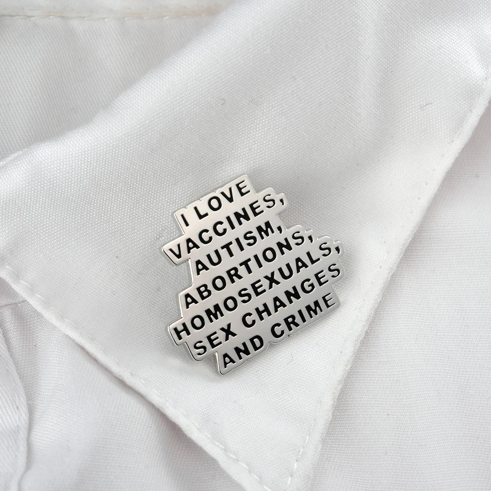 Pin on a white shirt with text 'I LOVE VACCINES, AUTISM, ABORTIONS, HOMOSEXUALS, SEX CHANGES AND CRIME'.