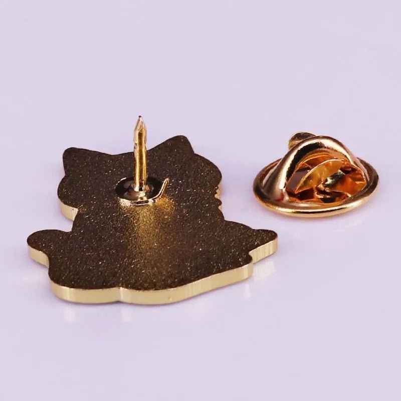 A close-up of the back of a Kiss Me Later gold-colored metal cat lapel pin, featuring a sharp post and butterfly clutch fastener—ideal for trendy accessory lovers or collectors of unique metal pins.