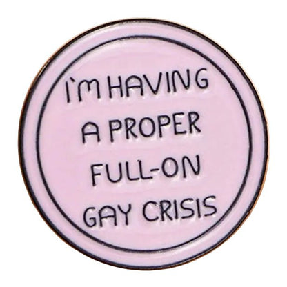 A round, light pink enamel pin titled "I'm Having A Proper Full-On Gay Crisis - Heated Rivalry," featuring the phrase "I'M HAVING A PROPER FULL-ON GAY CRISIS" in bold black capitals.