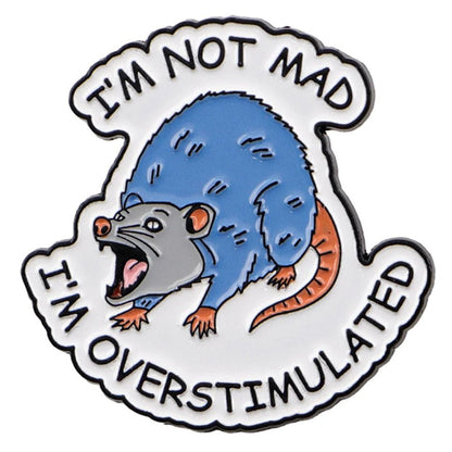 Enamel pin with a blue and gray possum illustration and text 'I'm not mad, I'm overstimulated' on a white background.