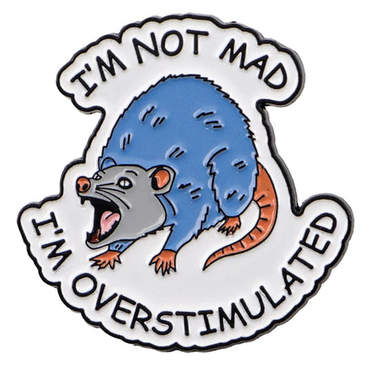 Enamel pin with a blue and gray possum illustration and text 'I'm not mad, I'm overstimulated' on a white background.