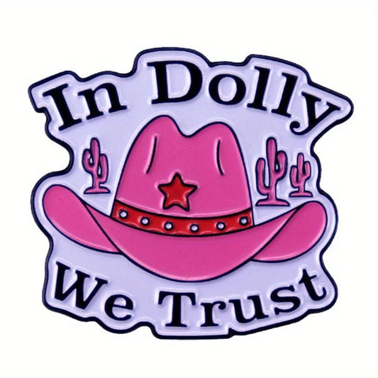 A pink cowgirl hat enamel pin called “In Dolly We Trust,” featuring a red star, cacti in the background, and the phrase “In Dolly We Trust” surrounding the hat.