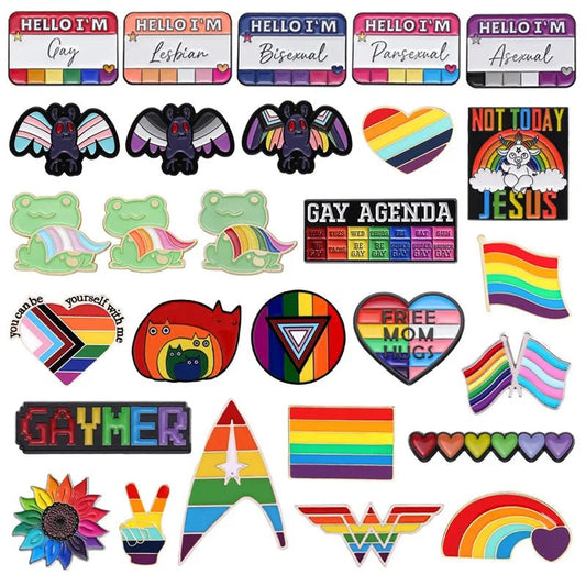 Presenting the LGBTIQ Rainbow Pride Enamel Pins by Gay Skate, a lively array of pride pins featuring colorful LGBTQ+ themed designs such as rainbows, pride flags, hearts, suns, and slogans like “Hello I’m Gay” and “Free Mom Hugs.” These pins also highlight motifs like frogs, angels, and peace symbols in a variety of pride colors.