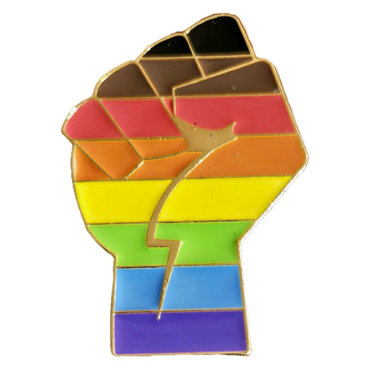 The Inclusive Rainbow Fist gold enamel pin features a raised fist with rainbow and inclusive pride flag colors, outlined in gold, symbolizing unity and solidarity.