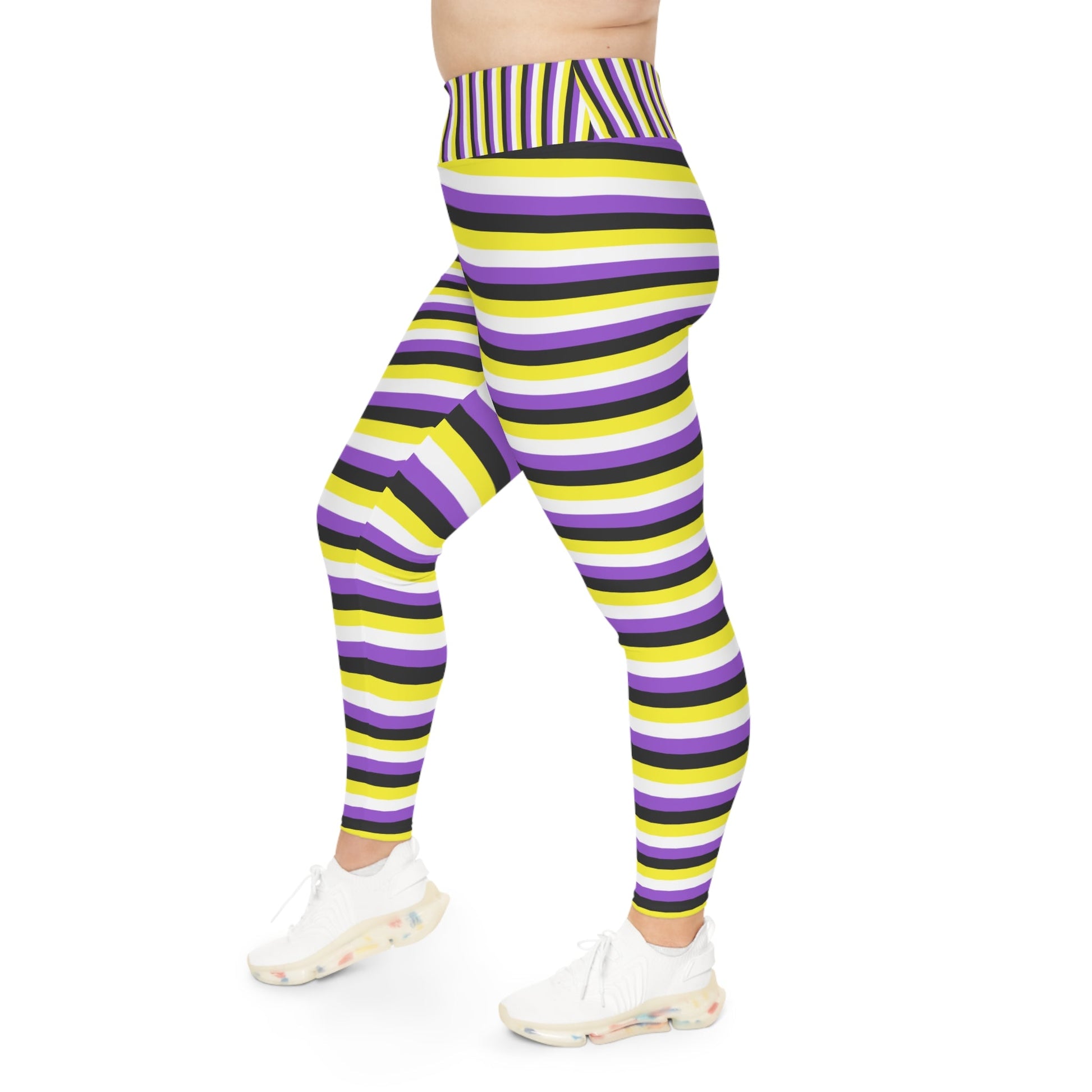 A person wearing Printify's Non-Binary Pride Flag Plus Size Leggings, sizes 2XL - 6XL, which feature high-waisted, colorful horizontal stripes in black, purple, yellow, and white. Made from 4-way stretch fabric for comfort and flexibility, they stand with their feet slightly apart. Only their legs and part of their torso are visible. They are also wearing white sneakers.