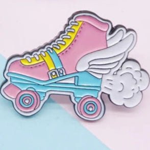 The Pansexual Pride Roller Skate with Wings enamel badge features a retro-style quad rollerskate adorned with wings, primarily pink with yellow and blue accents, enhanced by motion lines and puffs of cloud to illustrate speed.