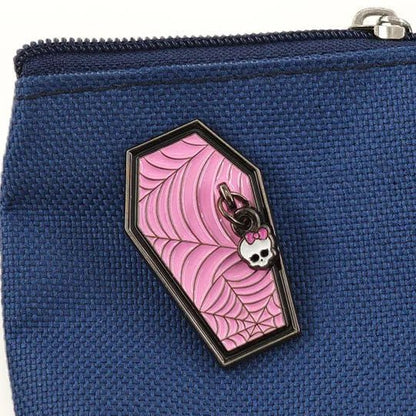 A coffin-shaped enamel pin with a pink spiderweb design and a small skull.