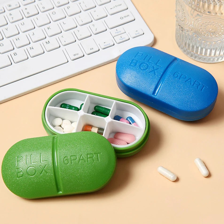 Three pill box cases in green, blue, with a few loose capsules nearby. The embossed text on the boxes reads 'PILL BOX' and '6PART'.