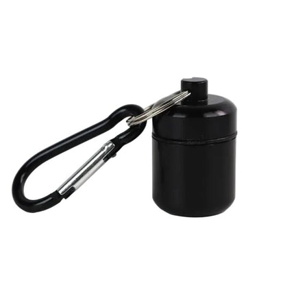 A small black waterproof cylindrical pill container with a screw-top lid, attached to a black carabiner via a small metal keys ring 