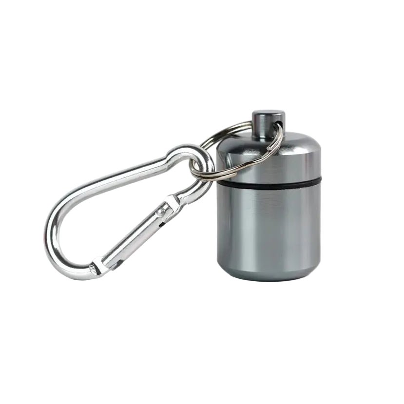A small aluminium grey cylindrical container attached to a silver carabiner for storing medication