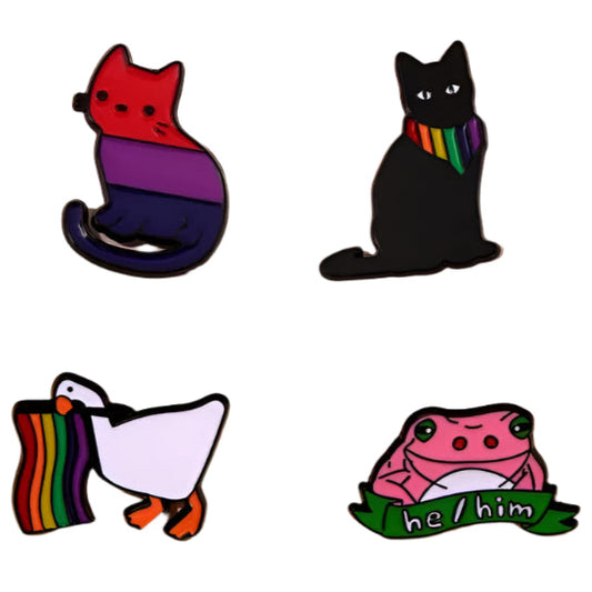 Four Pride Flag Enamel Pins from Gay Skate on a pink background. Top left: a bisexual cat. Top right: a rainbow pride black cat with a rainbow scarf. Bottom left: a rainbow duck. Bottom right: a he/him frog holding a "he/him" banner, celebrating queer identities.
