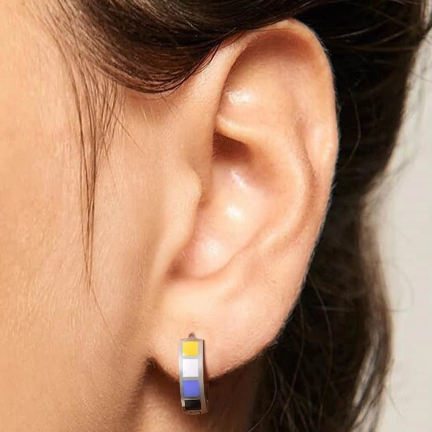 Close-up of a person wearing a non-binary pride flag hoop earring