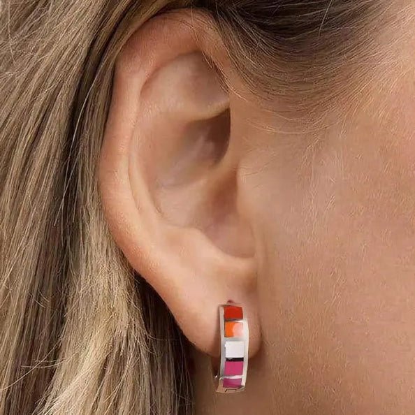 Close-up of a person wearing lesbian flag earrings