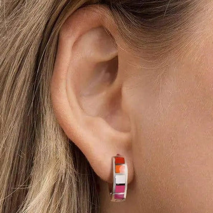 Close-up of a person wearing lesbian flag earrings