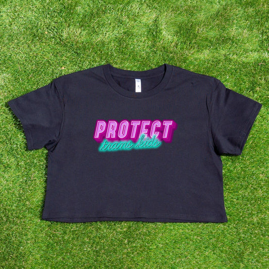 The Gay Skate's "Protect Trans Kids - original design - locally printed crop tee" is a black crop top t-shirt that proudly displays the text "PROTECT trans kids" in bold, vibrant pink and teal letters across the chest. The eye-catching font and incorporation of transgender pride flag colors make it a standout piece in queer skate and streetwear.