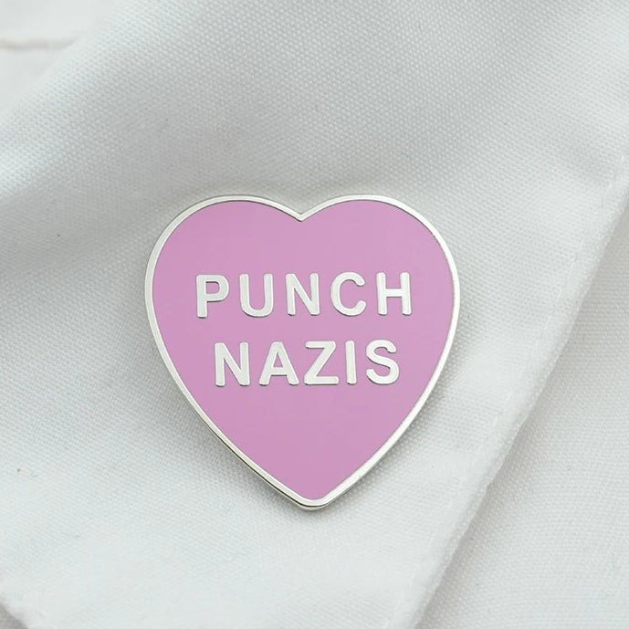 Heart-shaped pink enamel pin with 'PUNCH NAZIS' text 