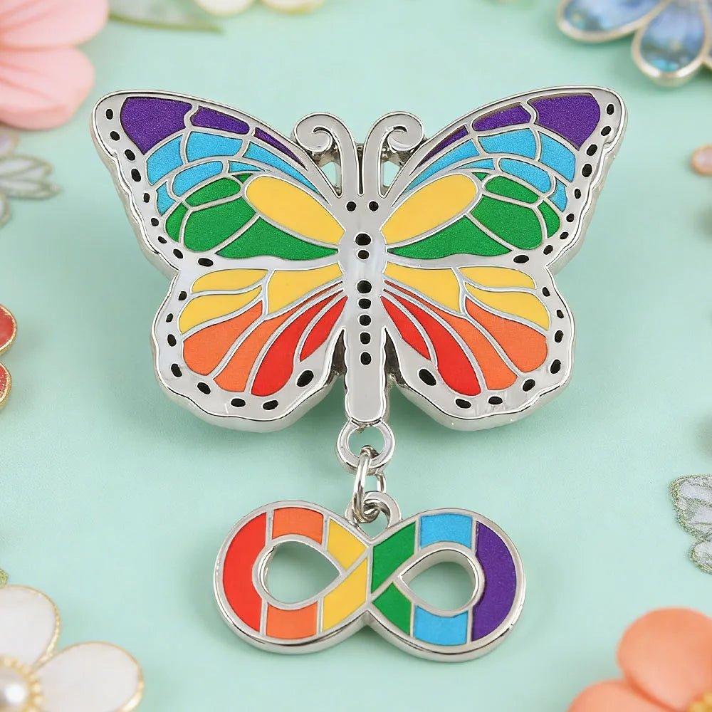 Butterfly-shaped pin with rainbow-colored wings and a hanging infinity symbol 