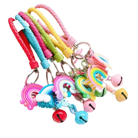 A lineup of colorful Rainbow Key Chains from Gay Skate, featuring kawaii pastel accessories, each adorned with playful charms like rainbows and round bells, showcased on a white background. These keychains, available in hues of red, pink, yellow, green, and blue, make perfect subtle pride wear.