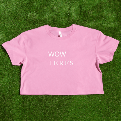A locally printed pink TERFS crop tee with "WOW TERFS" in white, hand-printed by a queer-owned small business, shown on green grass.